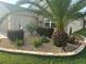 Landscaped garden bed with tropical palm trees, flowers, stone cover, and brick border at 11277 Se 170Th Ln, Summerfield, FL 34491