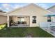 View of the backyard with a covered patio, grass area, and a side of the house in a neutral tone at 12430 Ne 52Nd Loop, Oxford, FL 34484