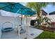 Outdoor patio space with grill, table, umbrella, and small trampoline, surrounded by a white fence and some landscaping at 12430 Ne 52Nd Loop, Oxford, FL 34484