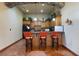 Basement bar area with wood cabinets, granite countertops, tile flooring, and bar stool seating at 12430 Ne 52Nd Loop, Oxford, FL 34484