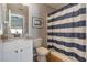 Cozy bathroom with a single sink vanity, toilet, and a shower/tub with a striped shower curtain at 12430 Ne 52Nd Loop, Oxford, FL 34484