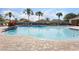 Community pool with a light blue water, multiple palm trees and lounge chairs and a white fence at 12430 Ne 52Nd Loop, Oxford, FL 34484