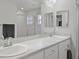 Bathroom featuring dual sinks, a large mirror, and a walk-in shower with tile surround at 1247 Mezzavalle Way, Auburndale, FL 33823