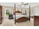 Spacious main bedroom featuring a four-poster bed, ceiling fan, and natural light from the windows at 12512 Lake Ridge Cir, Clermont, FL 34711