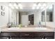 Bathroom with dual sinks, dark cabinetry, and large mirror reflecting the bedroom area at 1309 Piney Woods Path, The Villages, FL 32163
