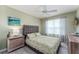 Comfortable bedroom features a queen-sized bed, gray cushioned headboard, ceiling fan, and natural light at 1309 Piney Woods Path, The Villages, FL 32163