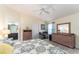 Cozy bedroom with stylish furniture, ceiling fan, and convenient access to a bathroom at 1309 Piney Woods Path, The Villages, FL 32163