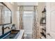Bathroom featuring black hardware, decorative sink, shelving and a shower/tub combo with patterned curtains at 13332 Via Roma Cir, Clermont, FL 34711