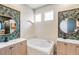 Bright bathroom with a soaking tub, white tiling, double vanities, decorative mirrors, and neutral decor at 13332 Via Roma Cir, Clermont, FL 34711