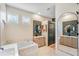 Bright bathroom with a soaking tub, white tiling, double vanities, decorative mirrors, and neutral decor at 13332 Via Roma Cir, Clermont, FL 34711