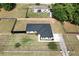 Bright aerial view of a modern home featuring a dark roof, white trim, and a spacious yard with partial fencing at 14350 Se 36Th Ave, Summerfield, FL 34491
