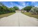 This home features an expansive driveway surrounded by mature trees, with a cozy front yard at 14490 Se 96Th Ter, Summerfield, FL 34491