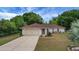 Charming single-Gathering home featuring a lush green lawn, mature trees, and an attached two-car garage at 14490 Se 96Th Ter, Summerfield, FL 34491