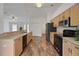 Bright kitchen boasts wood cabinets, black appliances, and sleek wood-look vinyl flooring at 14490 Se 96Th Ter, Summerfield, FL 34491