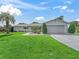 Inviting single-story home featuring a manicured lawn, mature landscaping, and an attached two-car garage at 17819 Se 105Th Ct, Summerfield, FL 34491