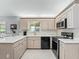 Modern kitchen featuring light wood cabinets, sleek black appliances, and white countertops at 17819 Se 105Th Ct, Summerfield, FL 34491