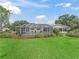 A beautiful backyard with a screened-in pool, lush landscaping, and a well-maintained lawn under a partly cloudy sky at 17819 Se 105Th Ct, Summerfield, FL 34491
