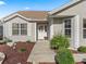 A close view shows the front door with a wreath, manicured landscaping, and tan siding at 17916 Se 87Th Melrose Ct, The Villages, FL 32162