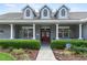 Inviting front porch with sturdy columns, a red front door, and lush landscaping along the walkway at 19624 Spring Oak Dr, Eustis, FL 32736