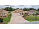 Aerial view of a home showcasing a brick driveway, manicured lawn, and mature landscaping at 1972 Palo Alto Ave, The Villages, FL 32159
