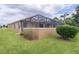 Exterior view of the screened-in pool and patio area, with well-maintained lawn and landscaping at 1972 Palo Alto Ave, The Villages, FL 32159