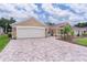 Charming single-story home boasts a well-manicured lawn, brick driveway, and attached two-car garage at 1972 Palo Alto Ave, The Villages, FL 32159