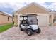 Well-maintained golf cart parked in front of a house with a brick driveway and a two-car garage at 1972 Palo Alto Ave, The Villages, FL 32159
