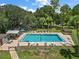 Aerial view of a community pool, surrounded by lounge chairs, lush greenery, and shade trees at 2110 Oak Cir, Mount Dora, FL 32757
