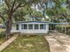 Charming single-story home with a wooden deck and a covered carport, framed by mature trees and a green lawn at 2110 Oak Cir, Mount Dora, FL 32757