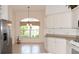 Cozy breakfast nook area with stainless steel refrigerator and white cabinets illuminated by a large window at 2120 Willow Grove Way, The Villages, FL 32162