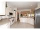 Well-equipped kitchen featuring white cabinetry, tile flooring, stainless steel appliances, and an open layout at 2120 Willow Grove Way, The Villages, FL 32162