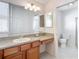 Bathroom featuring a vanity with a sink, spacious countertop, and well-lit mirror, next to a toilet and shower at 2202 Kershaw Rd, The Villages, FL 32162