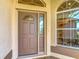 Close-up of a stylish brown front door with decorative glass, framed by an arched window and situated next to a half round window at 2202 Kershaw Rd, The Villages, FL 32162