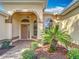 Inviting front entrance with a covered porch, arched entryway, beautiful landscaping, and a stylish front door with decorative glass at 2202 Kershaw Rd, The Villages, FL 32162