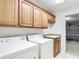 Functional laundry room with washer, dryer, sink, and wooden cabinets for ample storage space at 2202 Kershaw Rd, The Villages, FL 32162