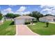 Charming one-story home featuring a well-maintained lawn, flowering bushes and a golf cart driveway at 2369 Five Forks Trl, The Villages, FL 32162