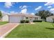 Charming one-story home featuring a well-maintained lawn, flowering bushes and a golf cart driveway at 2369 Five Forks Trl, The Villages, FL 32162