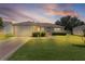 Charming single-story home featuring a well-manicured lawn and attached one car garage at dusk at 2369 Five Forks Trl, The Villages, FL 32162