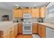 Bright kitchen featuring white appliances, wood cabinets and hardwood floors at 2369 Five Forks Trl, The Villages, FL 32162