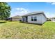 Backyard view of a gray house with a covered patio and a large grassy area at 23707 Companero Dr, Sorrento, FL 32776