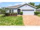 Charming single-story home featuring a well-manicured lawn, brick driveway, and a two-car garage at 23707 Companero Dr, Sorrento, FL 32776