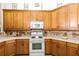 A closer view of the kitchen with a white range, microwave, and wood cabinetry at 2457 Bar Harbor, Mount Dora, FL 32757