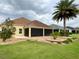 Well-maintained backyard with a covered patio, lush lawn, and tropical landscaping at 2918 Canyon Ave, The Villages, FL 32163