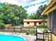 Backyard with a pool, fence, lush trees, and a quaint yellow home at 308 Sunnyside Dr, Leesburg, FL 34748