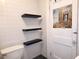A bathroom featuring black floating shelves mounted on a white tiled wall above the toilet at 308 Sunnyside Dr, Leesburg, FL 34748