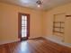 Bedroom featuring an exterior door, neutral wall paint, hardwood floors, and built-in shelving at 308 Sunnyside Dr, Leesburg, FL 34748