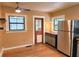 Kitchen featuring stainless steel refrigerator, rustic wood floors, and view to screened porch at 308 Sunnyside Dr, Leesburg, FL 34748