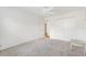 A bright bedroom with light gray carpet, white walls, ceiling fan, closet, and an adjacent hallway entrance at 3118 Sweetgum St, The Villages, FL 32163