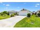 Well-maintained home featuring a manicured lawn, mature landscaping, and a driveway leading to an attached two-car garage at 3118 Sweetgum St, The Villages, FL 32163