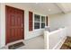 Welcoming front porch with a red door, white railings, and a comfortable chair at 3118 Sweetgum St, The Villages, FL 32163